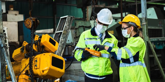 Industrial engineer in suite and safety helmet working in factory, planning and training